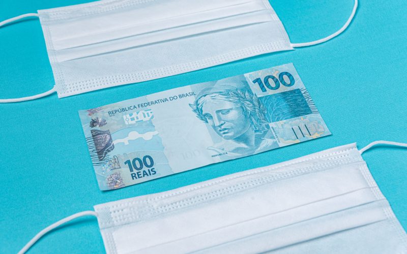 Surgical mask and brazilian real money, on the light blue background